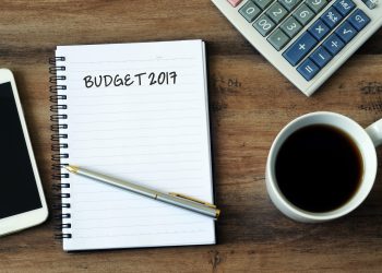 Business concept - Text Budget 2017 on a notepad with smart phone, pen, coffee and calculator on a wooden table with copy space.